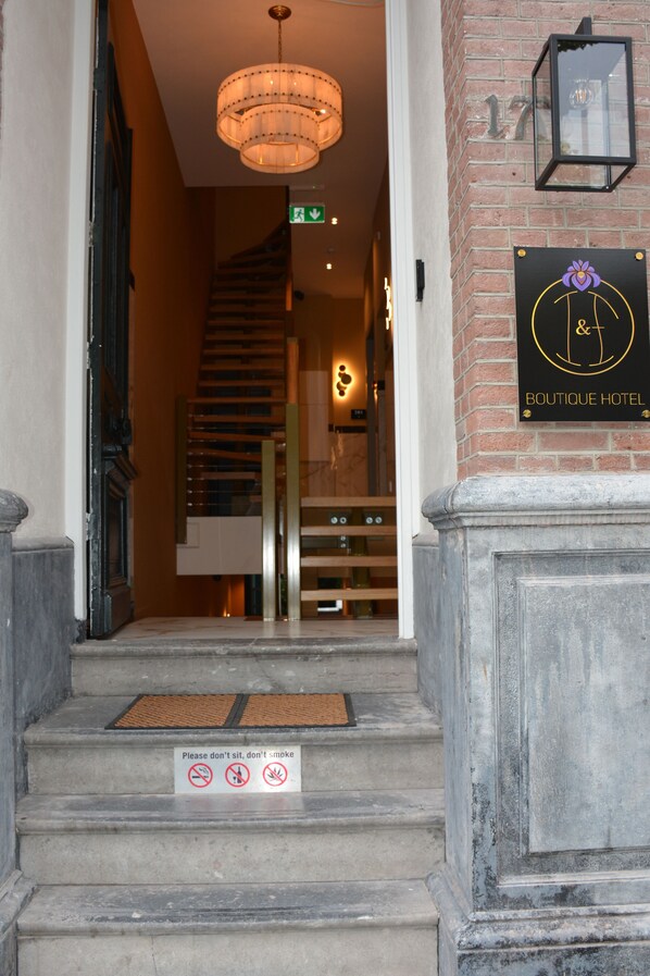 A hotel entrance with a staircase, a sign prohibiting sitting and smoking, and a sign for the Boutique Hotel. - If boutique hotel (Amsterdam)