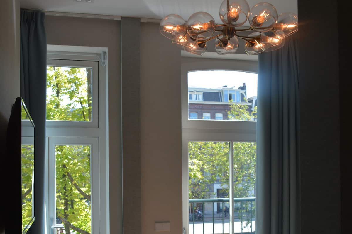 A bedroom with a large bed, a chair, a table, and a chandelier.