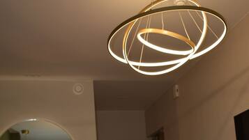 A bedroom with a bed, a round mirror, and a modern light fixture.