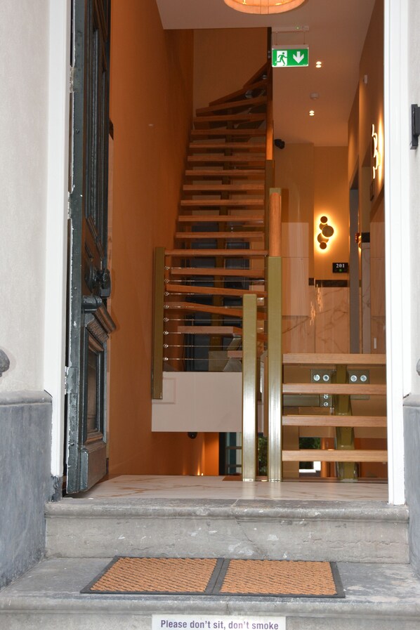 A hotel entrance with a staircase, a doormat, and a sign indicating the location.