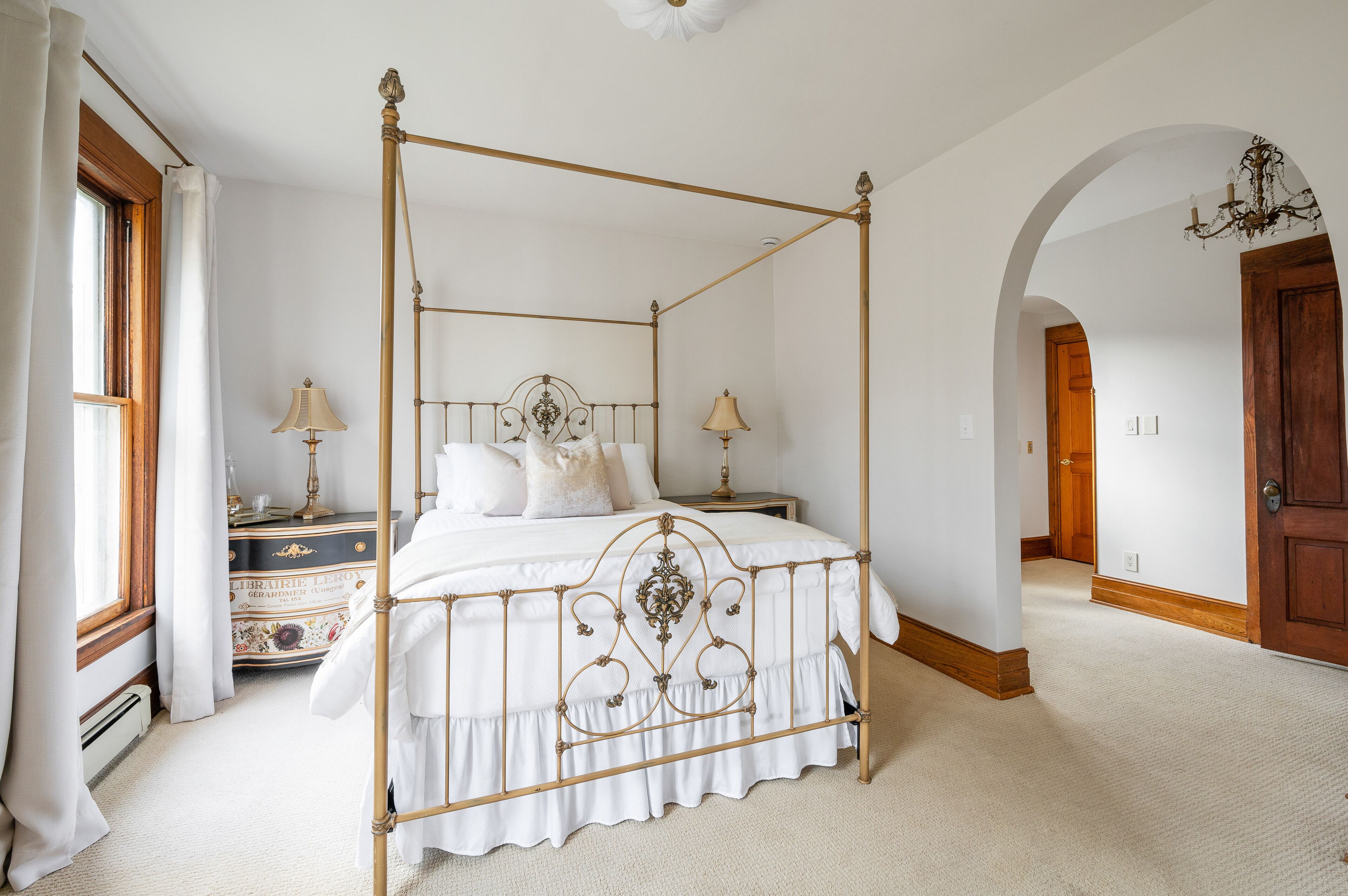 Una cama con dosel de madera, un aparador con diseño floral y un candelabro.
