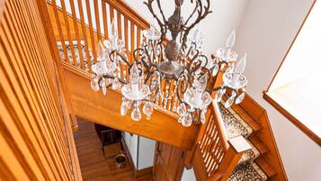 A wooden staircase with a chandelier and patterned carpet.
