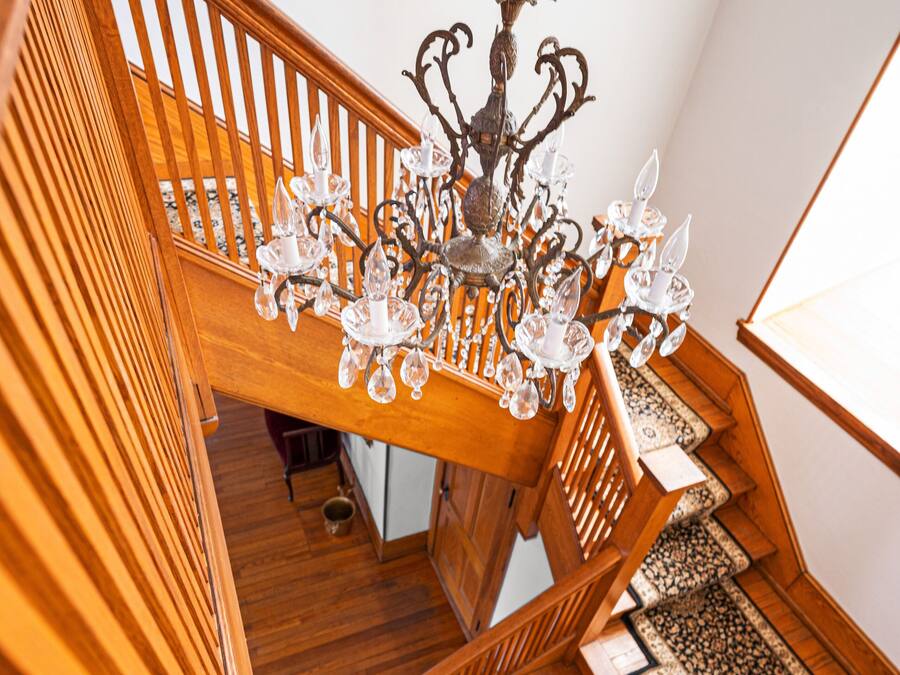 A wooden staircase with a chandelier and patterned carpet.