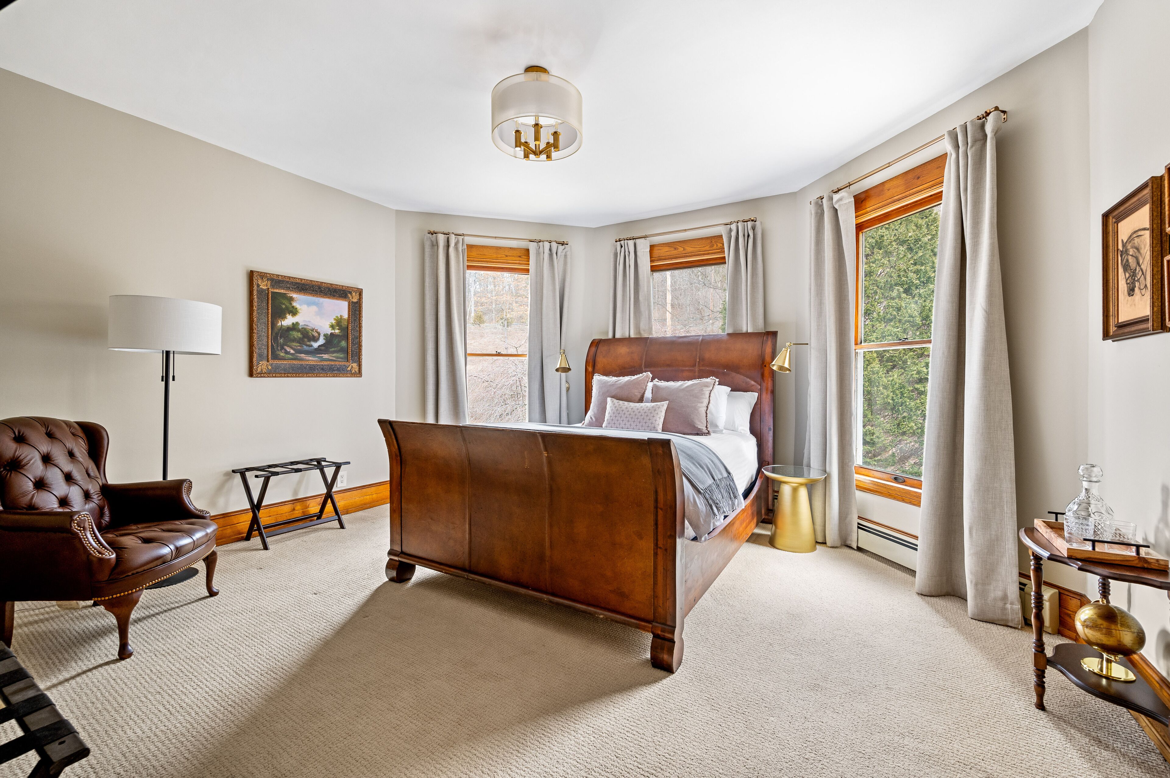 A bedroom with a large bed, a chair, a lamp, and a window with curtains.