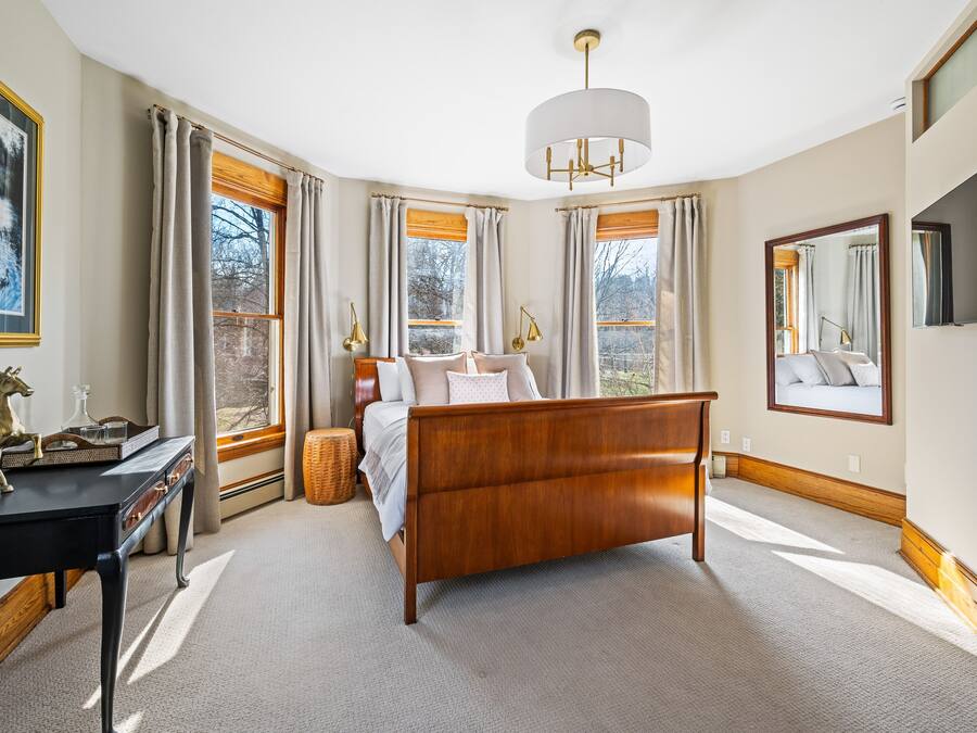 Un dormitorio con una cama de madera, un escritorio y un ventanal con cortinas.