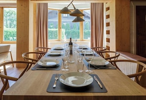 A dining table set for six with chairs, a bottle of wine, and glasses.