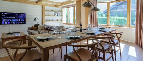 A dining area with a wooden table set for six, surrounded by chairs.