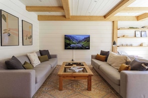 A living room with two sofas, a coffee table, a flat-screen TV, and a bookshelf.
