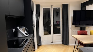 Une cuisine moderne avec des meubles de couleur noire, une cuisinière encastrée et un coin repas comprenant une table et des chaises en bois.