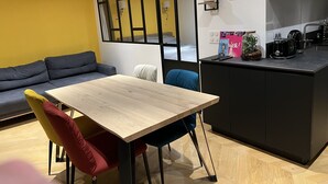 Une cuisine moderne avec une table et des chaises en bois, un plan de travail noir et un mur jaune.