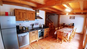 Una cocina con armarios de madera, un refrigerador Bosch, una estufa y una mesa de comedor con sillas.