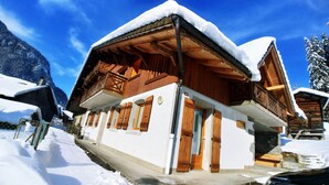 Un edificio de estilo chalete tradicional, con fachada de madera, paredes exteriores blancas y un balcón.
