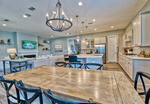 A spacious kitchen with a wooden dining table, white cabinets, and a chandelier. - Ocean View * 5BR Luxury Single Family House! (Ocean View)