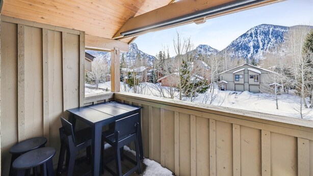 A wooden cabin with a dining area and a view of snow-covered mountains.