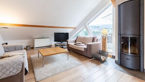 Une chambre de style loft moderne, avec un plafond en pente, une cheminée, une grande fenêtre et un coin salon confortable.