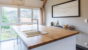 Une cuisine moderne avec un plan de travail en bois, un évier et une recette encadrée accrochée au mur.