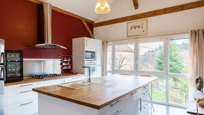 Une cuisine moderne dotée d’un plan de travail en bois, de meubles blancs, d’un four encastré et d’une grande fenêtre donnant sur l’extérieur.