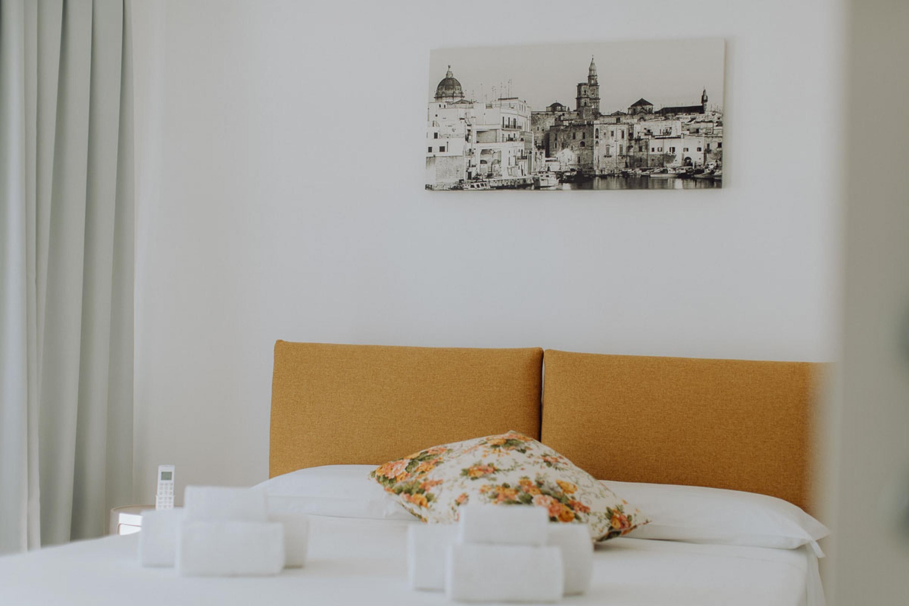 A hotel room with a bed, a pillow, and a wall-mounted picture of a cityscape.