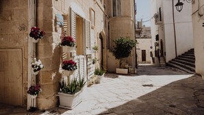 A narrow cobblestone street with buildings on either side, some with flower boxes and potted plants. - Casa Vacanze Portanuova Monopoli (Monopoli)