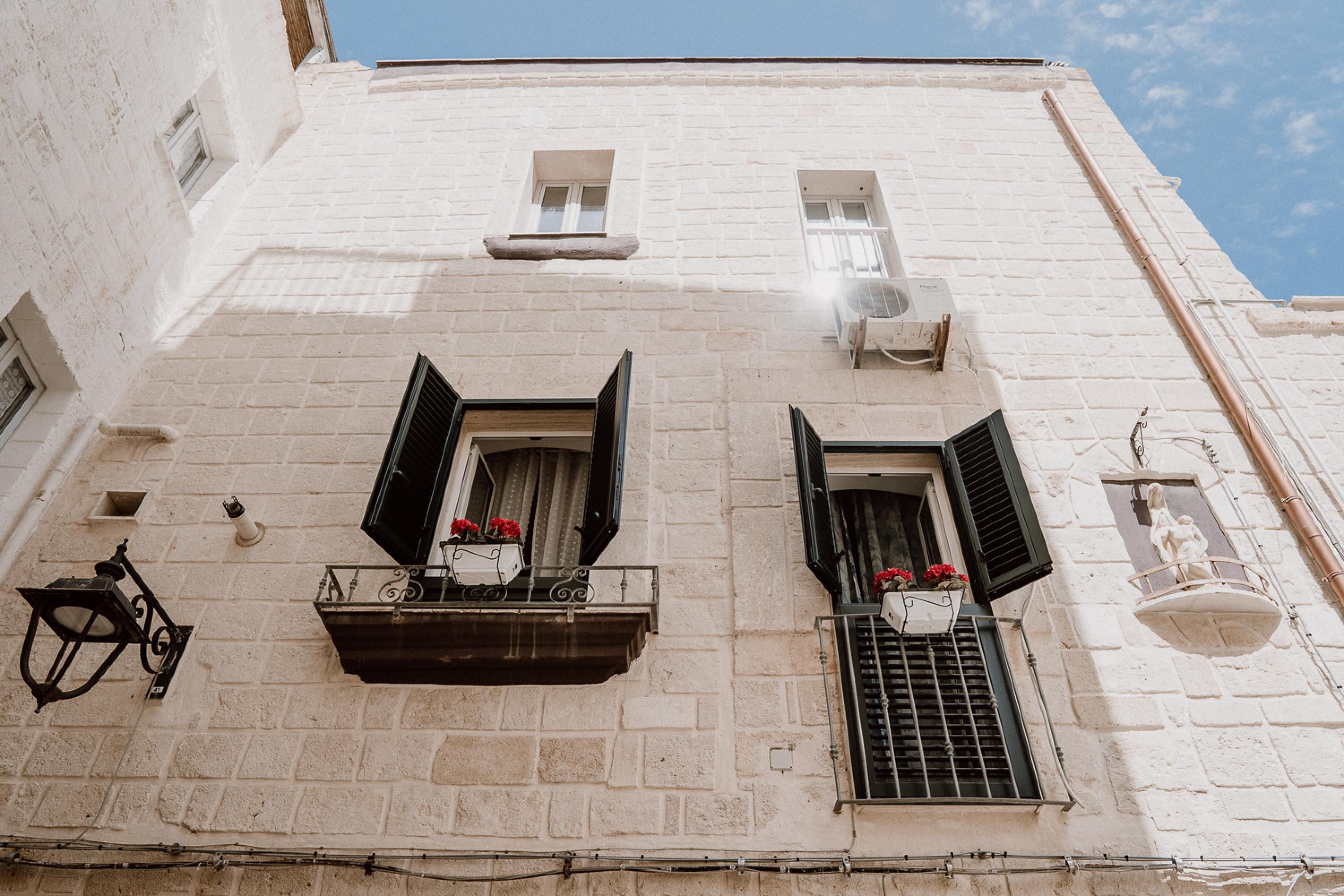 A white building with two windows, each with black shutters and a flower box.