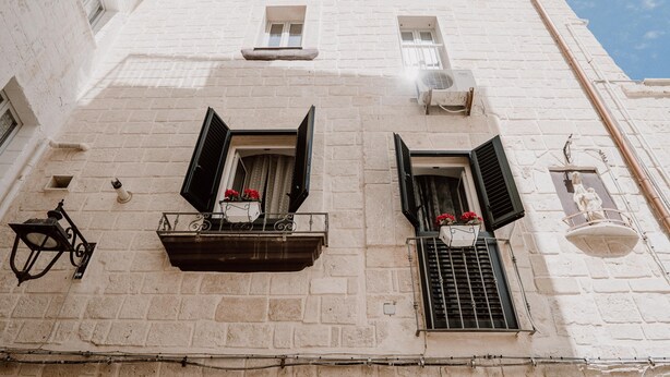 A white building with two windows, each with black shutters and a flower box. - La Dimora di Stesa in Monopoli (Monopoli)