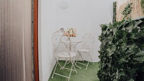 A small room with a white wall, a wooden door, a small table with two chairs, and a green artificial grass floor. - La Dimora di Stesa in Monopoli (Monopoli)