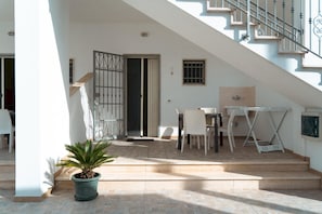 A staircase leading to a second floor, a dining area with a table and chairs, and a potted plant. - Appartamento 69 in Casalabate (Squinzano)