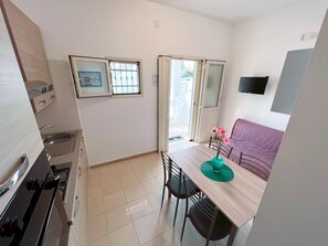 Uma cozinha compacta com fogão, pia e um espaço de jantar com mesa e cadeiras.