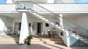 A modern two-story house with a staircase, outdoor seating area, and a potted plant. - Appartamento 69 in Casalabate (Squinzano)