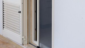 A white door with a sliding glass panel, a white shutter door, and a small wooden sign with a sailboat and the text "Enjoy the Beach". - Appartamento 73 in Casalabate (Squinzano)
