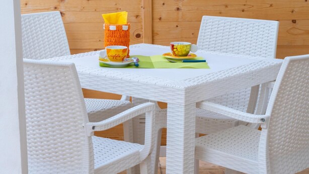 A white wicker table with four chairs, a yellow basket, and a floral cup on a green placemat. - Appartamento 73 in Casalabate (Squinzano)