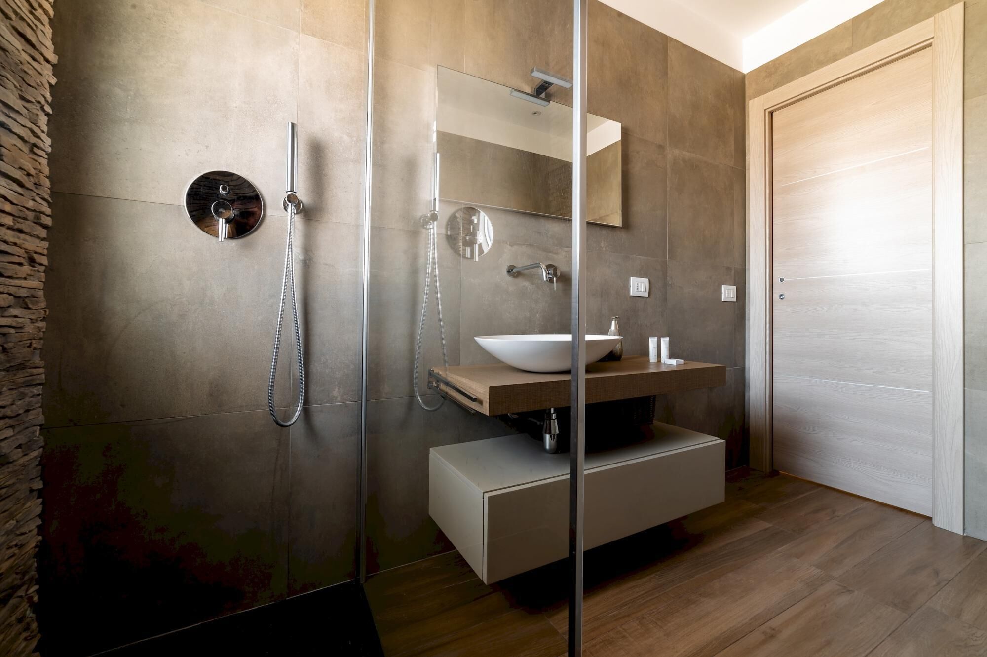 Une salle de bain moderne avec une douche à parois de verre, un lavabo blanc et un meuble-lavabo en bois.