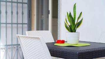 Uma pequena mesa com uma planta em vaso, um objeto vermelho e um jogo americano verde.