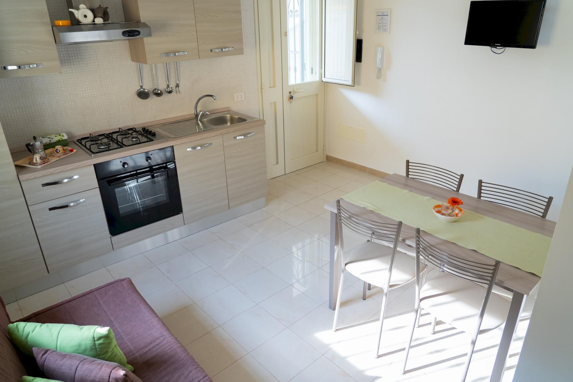 Uma cozinha moderna com fogão a gás, forno e pia. Há uma área de refeições com mesa e cadeiras.