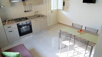 Uma cozinha moderna com fogão a gás, forno e pia. Há uma área de refeições com mesa e cadeiras.
