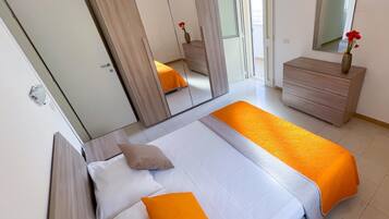 Quarto com uma cama, penteadeira, espelho e porta.