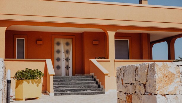 A building with a central door, a staircase leading to the entrance, and a potted plant beside the steps. - Villa Carla al Capitolo (Monopoli)