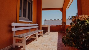 A balcony with a white bench, a small table, and potted plants. - Villa Carla al Capitolo (Monopoli)