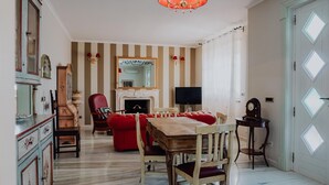 A dining area with a wooden table and chairs, a red sofa, a television, and a fireplace. - Villa Carla al Capitolo (Monopoli)
