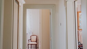 A hallway with a chair, white walls, and a ceiling vent. - Villa Carla al Capitolo (Monopoli)