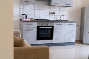 A modern kitchen with grey cabinets, a built-in oven, and a gas stove. - Appartamento 74 in Casalabate (Squinzano)