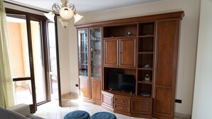 A living room with a large wooden cabinet, a flat-screen TV, and two ottomans. - Elle Dimore in Lecce (Lecce)