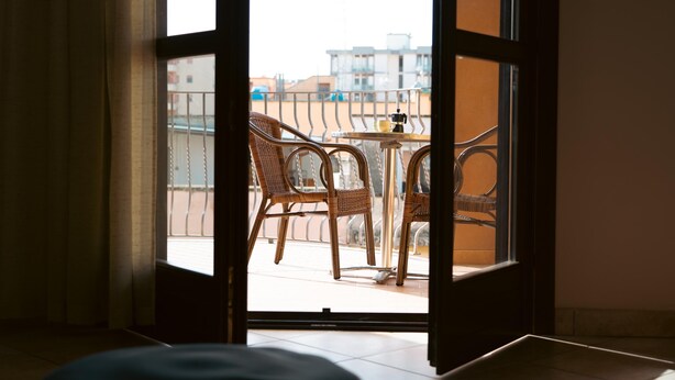 An open door leading to a balcony with wicker chairs and a small table. - Elle Dimore in Lecce (Lecce)