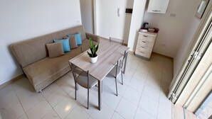 Een moderne woonkamer met een bank, een eettafel en een plant in pot.