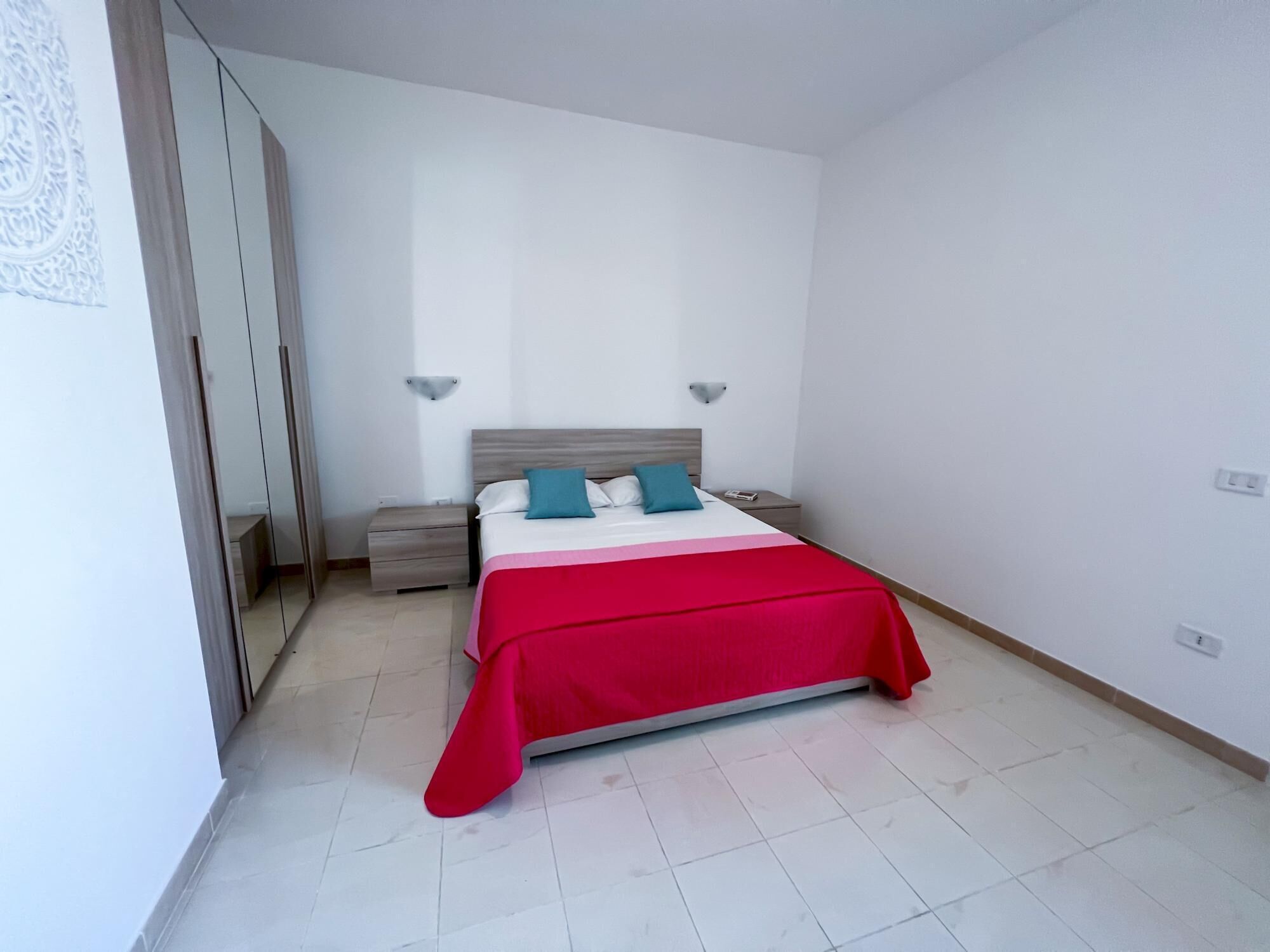 A bedroom with a bed, nightstands, and a wardrobe.