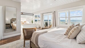 A bedroom with a large bed, a ceiling fan, and a view of the ocean through large windows. - Pet-Friendly Beach House w/ Heated Pool (Port St. Joe)