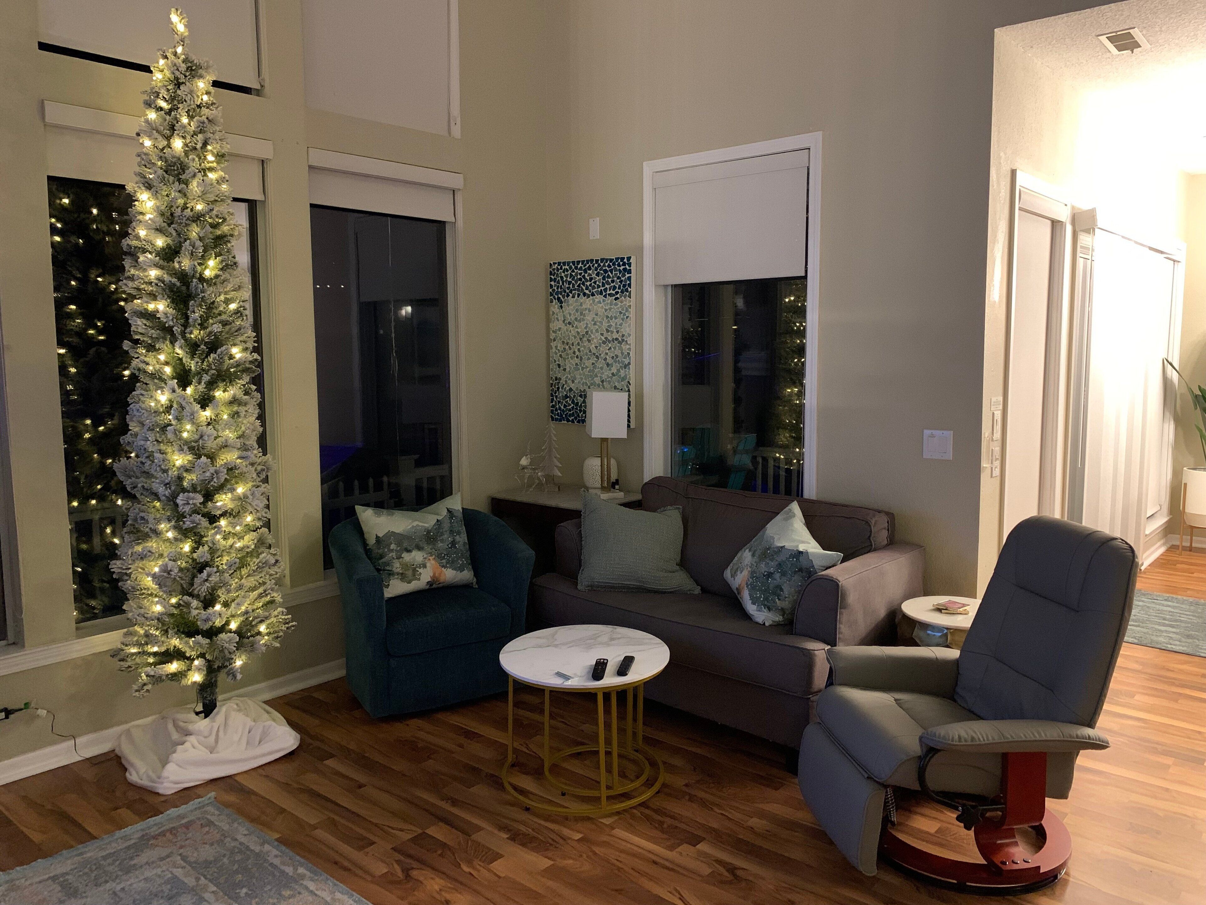 Una sala de estar con un árbol de Navidad, un sofá, una silla y una mesa de centro.