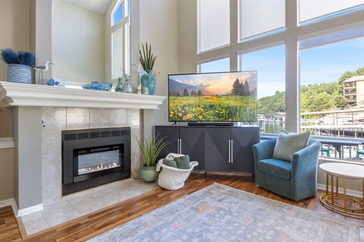 Una sala de estar con chimenea, televisor y vistas a un paisaje urbano a través de amplios ventanales.