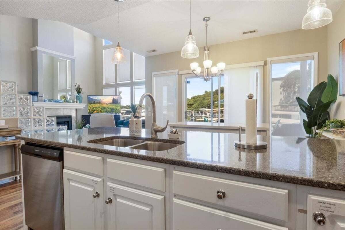 A modern kitchen with granite countertops, stainless steel appliances, and pendant lighting.