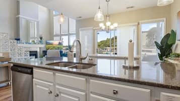 A modern kitchen with granite countertops, stainless steel appliances, and pendant lighting.